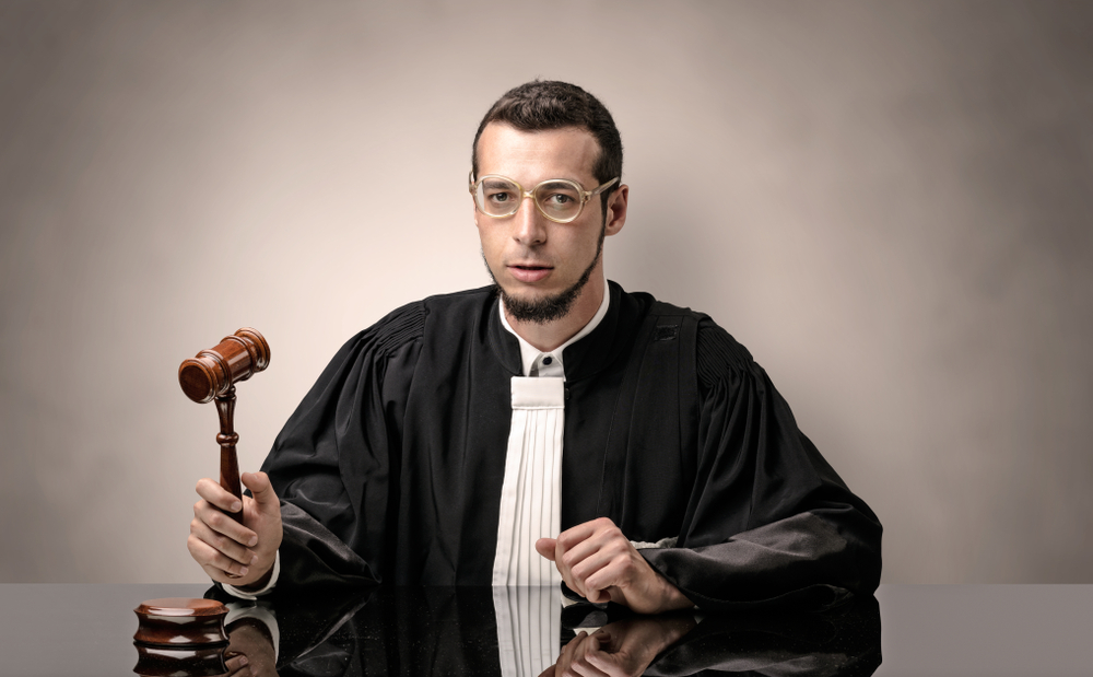 Young dashing judge in black gown making decision with no concept